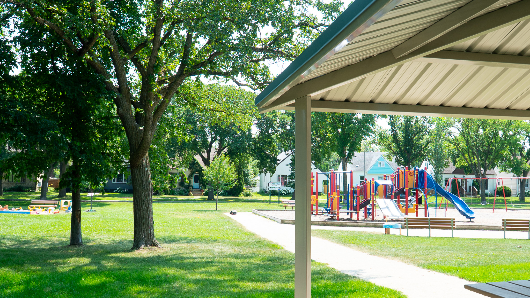 Playground with slides and swings seen from a shaded picnic shelter at Harrow Park